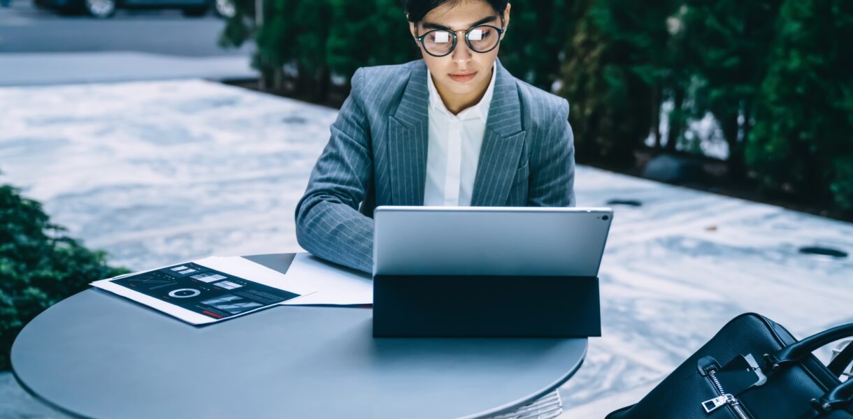 Businesswoman working at tablet in outdoors cafe