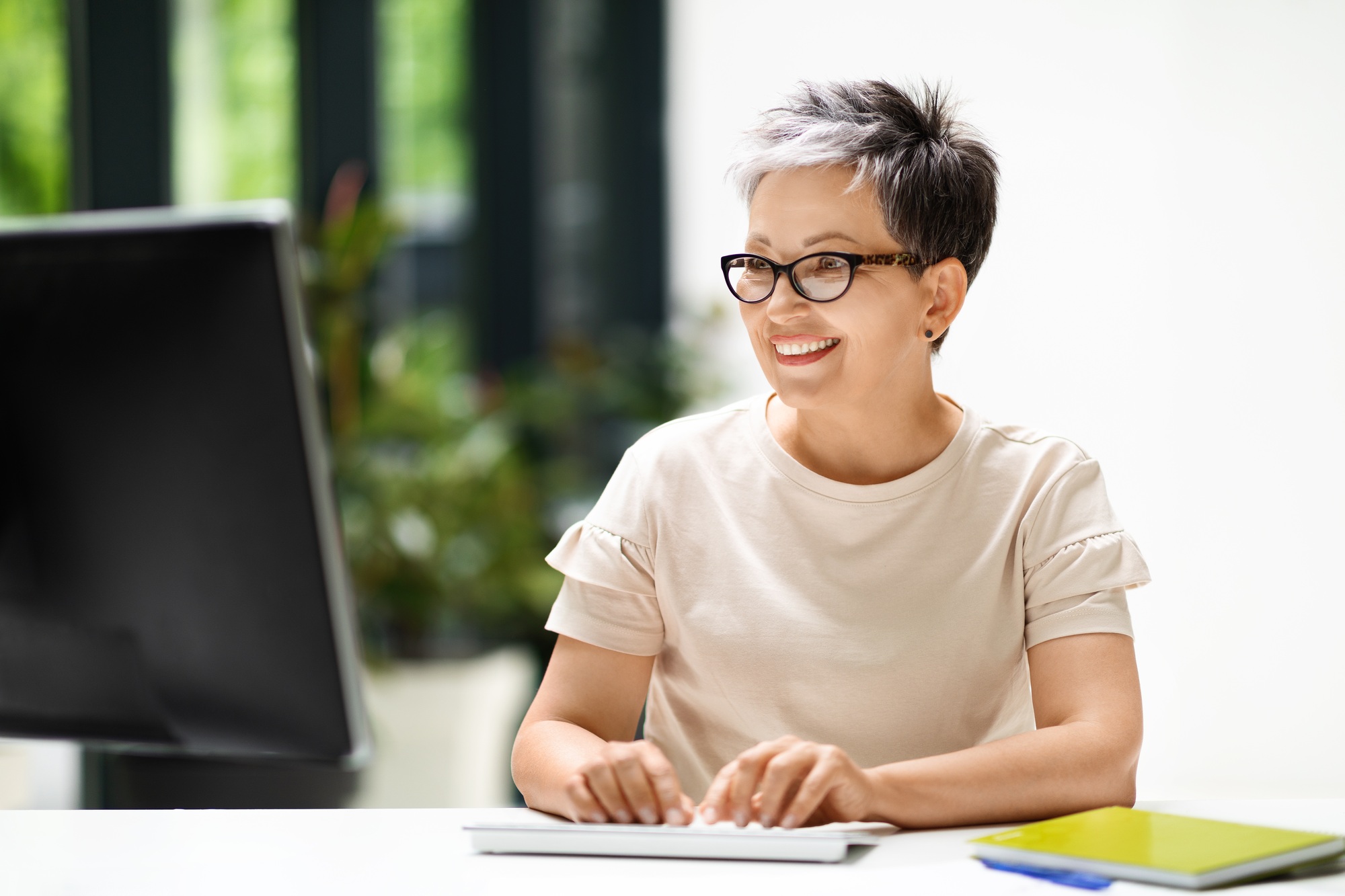 Cheerful mature woman working from home office on computer pc